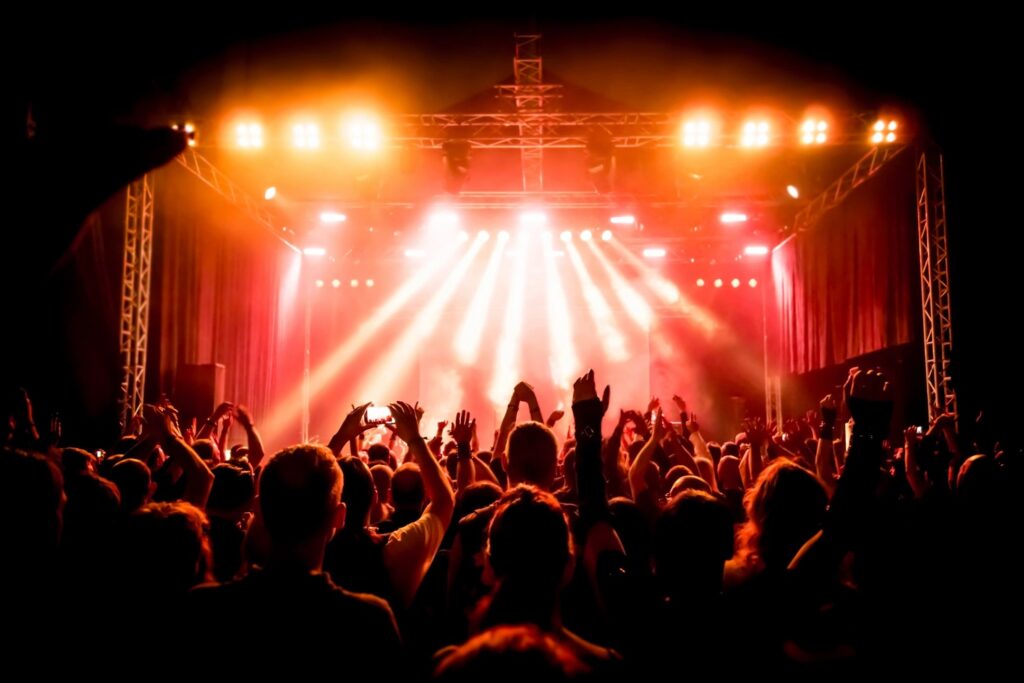 A crowd of people in front of a stage with lights.