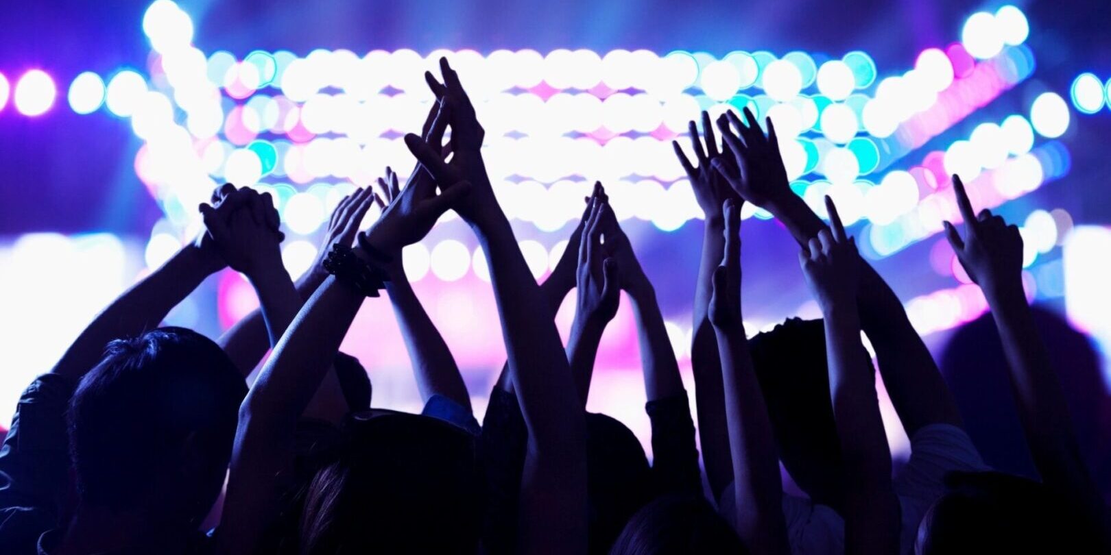 A crowd of people at an event with their hands in the air.